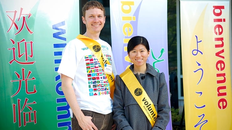Two international relations majors stand proudly in front of banners that say ?welcome? in many languages.