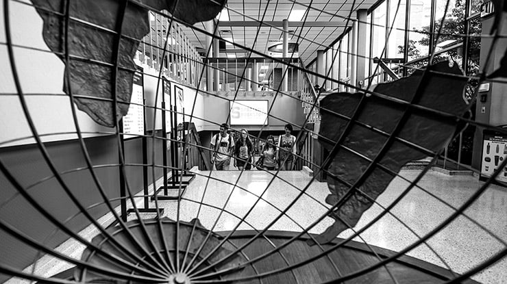 A black-and-white photo of social science education students walking up the stairs in a building on campus.