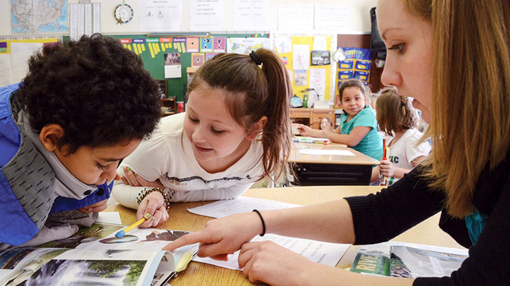 A student working on a special education degree teaches two young children at a classroom table.