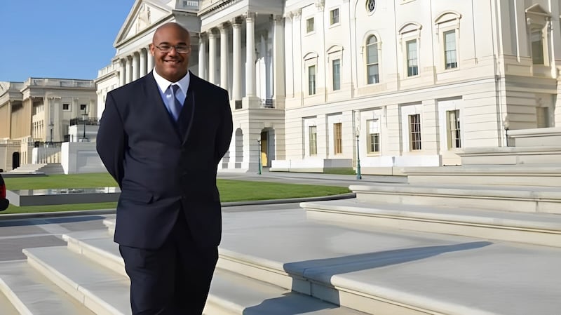 Man in suit standing in front of the Capitol