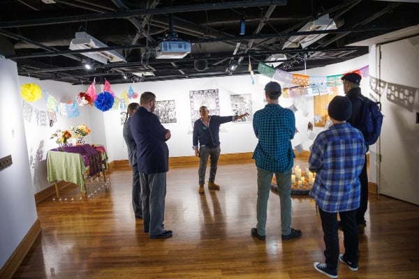 An RCAH instructor at MSU guides a group of students through an exhibit featuring cultural displays.