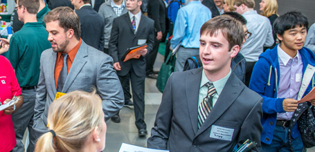 A student in a suit talks with an employer at a Michigan State University career fair.