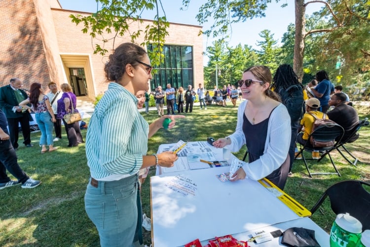 An MSU student is assisted at an outdoor table by OCAT