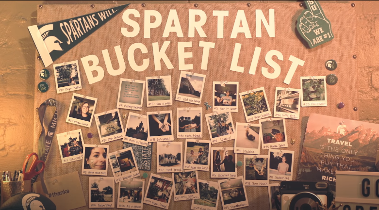 A collection of printed photographs, a foam finger, buttons and a pendant all pinned to a large cork board under the title "Spartan Bucket List"