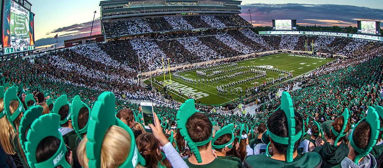 Students at Michigan State University's Spartan Stadium cheer on the football team.