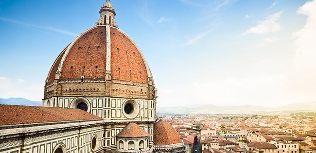 The iconic red dome of Florence’s Cathedral of Santa Maria del Fiore rises above the city rooftops under a soft, hazy sky.
