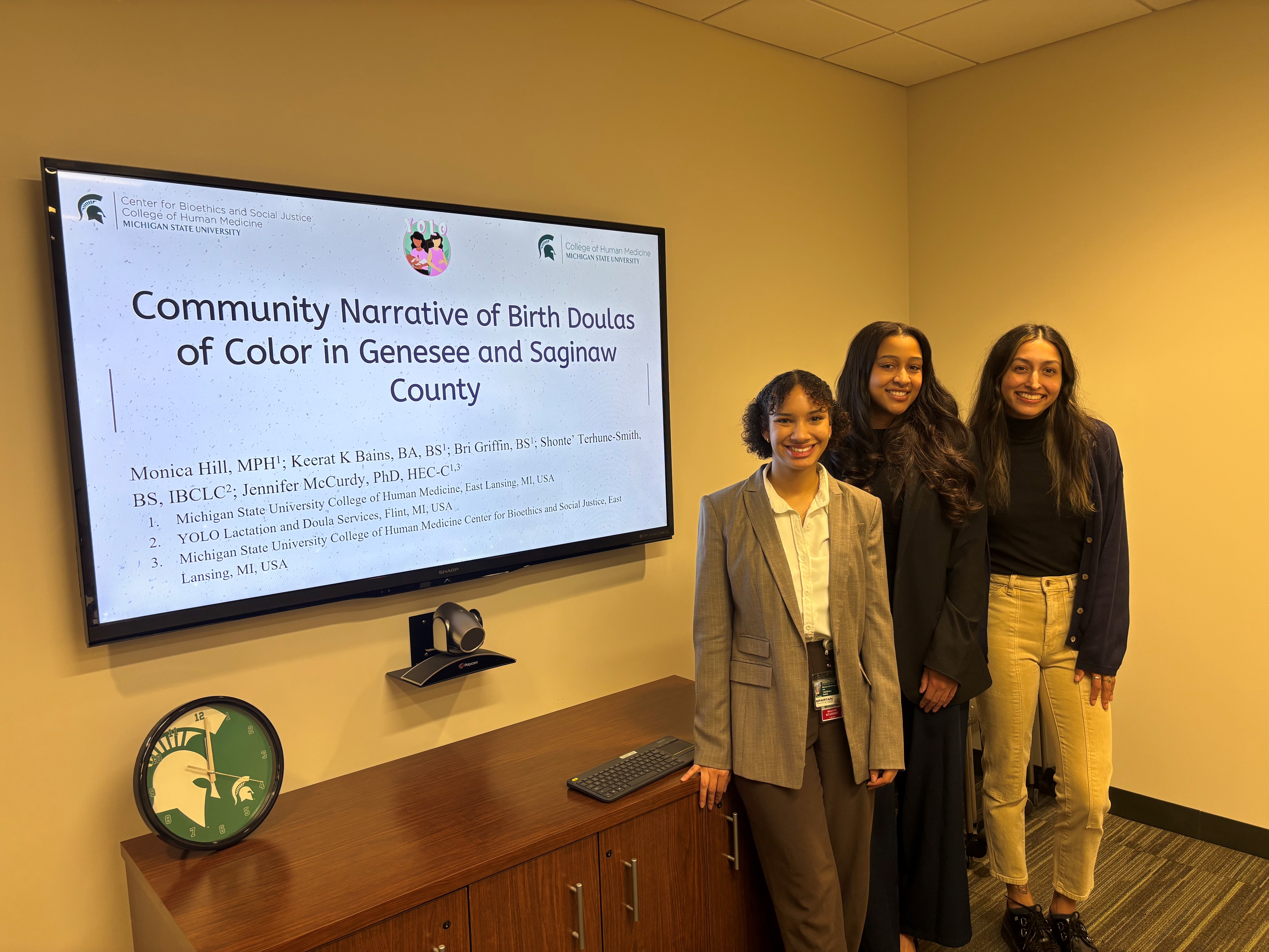Three students stand with research presentation