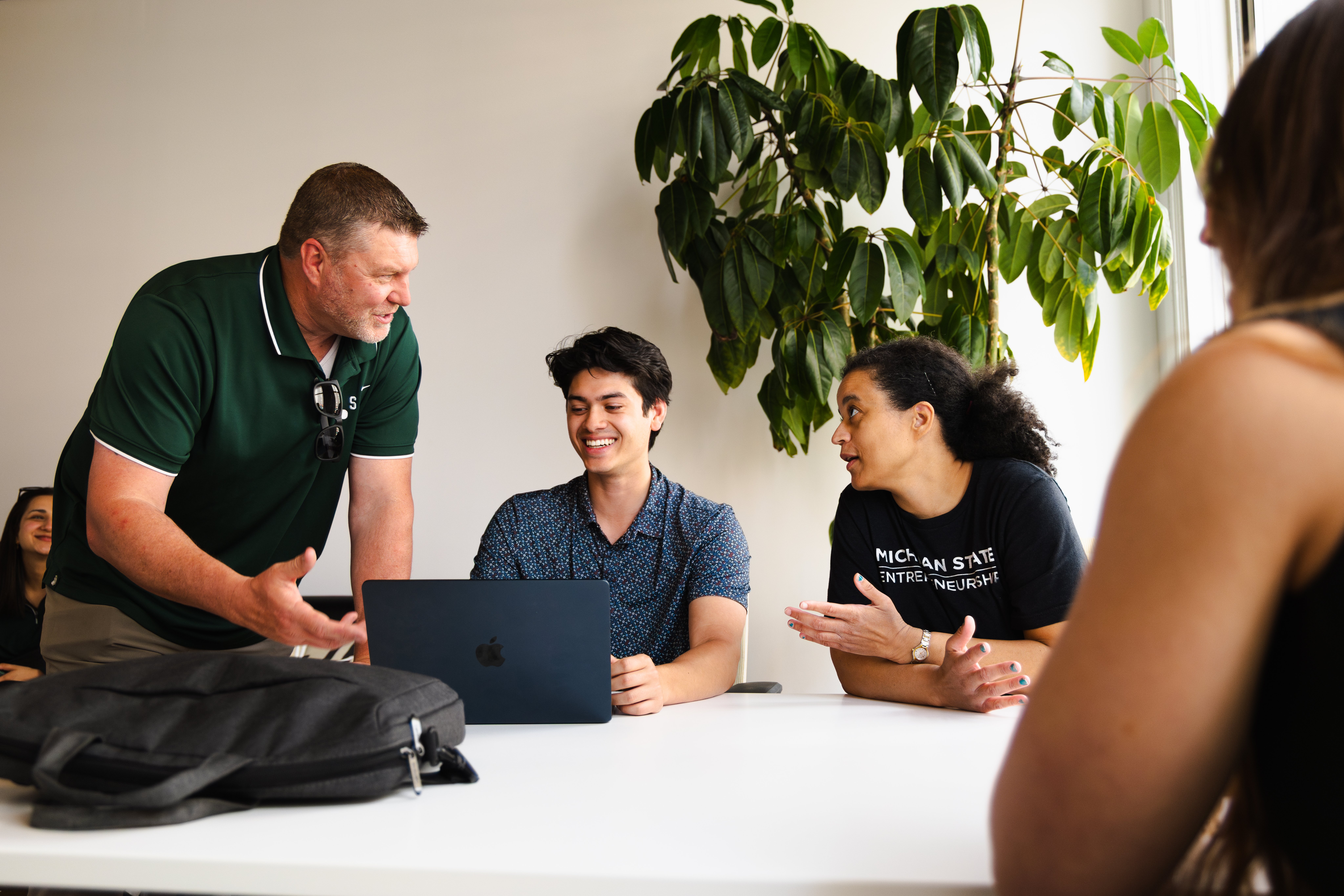 Group of people collaborating at a table with a laptop