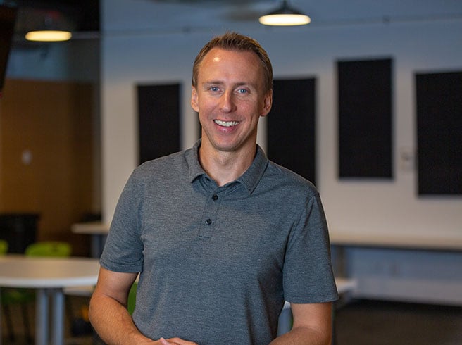 Ken Szymusiak, managing director, academics, poses in a grey polo