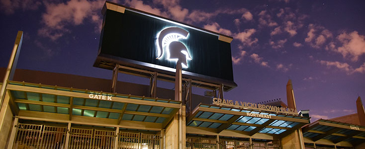 Close up of the Spartan Stadium at night. The Spartan helmet has lights behind it, illuminating the helmet. 