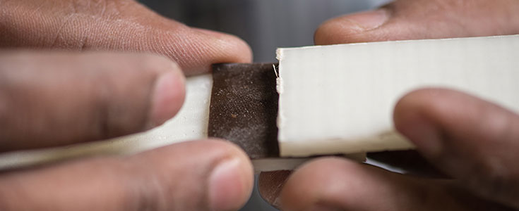 a close up of Mahmood Haq, assistant professor of civil and environmental engineering, hands displaying a composite material at the composite vehicle research center 