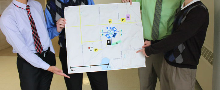 MSU college of engineering students showcasing a poster of one of their projects. a map of an area with highlighted parts is on the poser