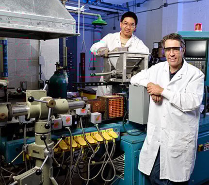 Two people in lab coats by a machine