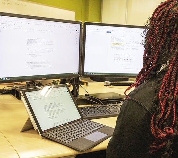 Student engaged with a laptop and computer during an EGR 102 class session.