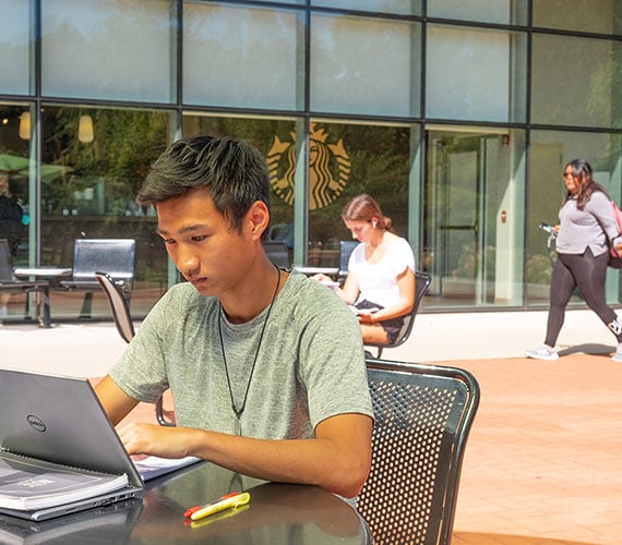 MSU Student sitting outside while on a laptop