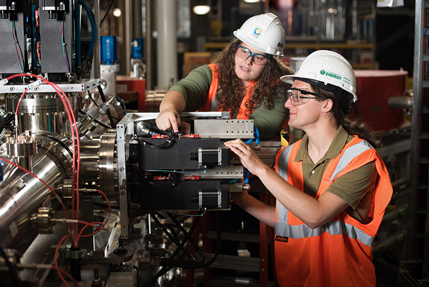 Graduate Assistant Christopher Richard (right) and Diagnostic Research Scientist Rebecca Shane inspect the controls for a system used to select ion-beam charge states.