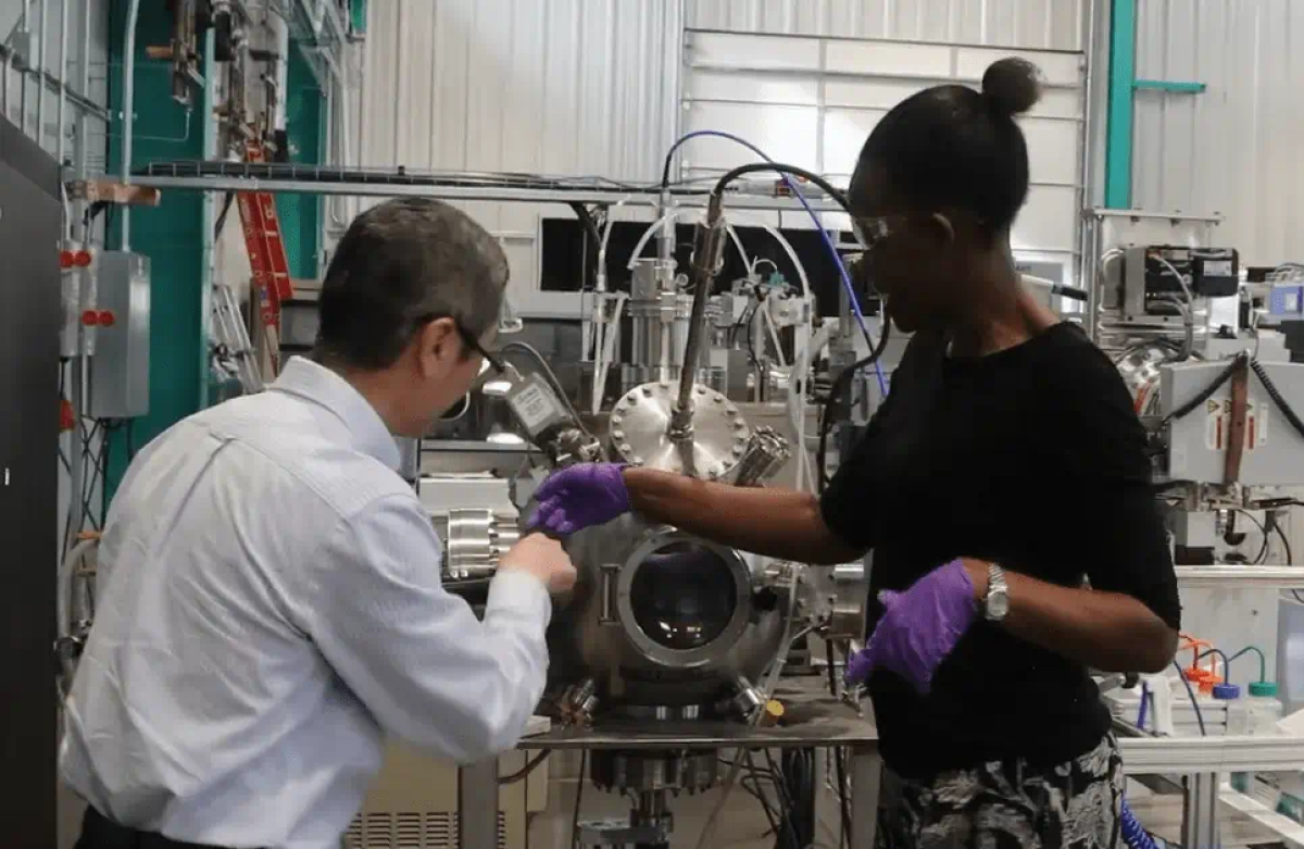 Two people facing machinery while they work