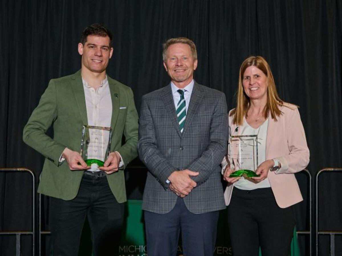 Innovation of the Year award for Sit Sense is presented to Justin Scott and Tamara Reid Bush by MSU President Kevin Guskiewicz