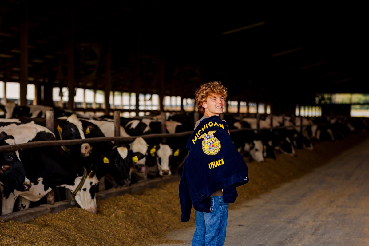 Brent DeSaegher looking over his shoulder as he stands in front of cows in a stall.