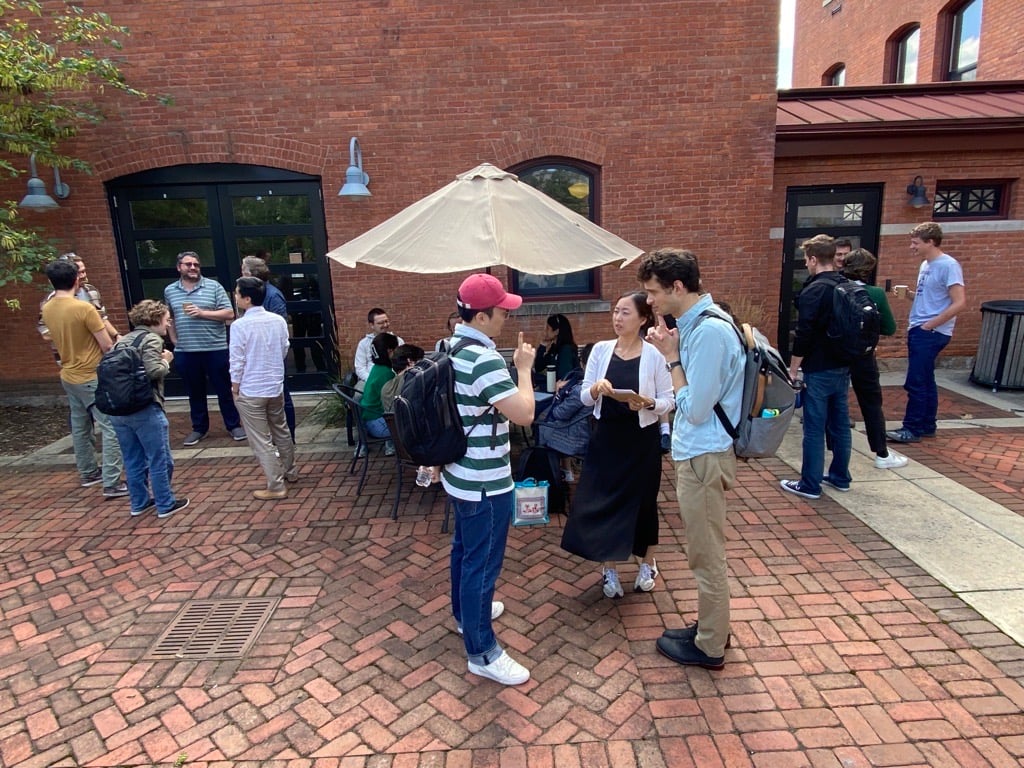 Faculty and graduate student discussions outside of a brick building.
