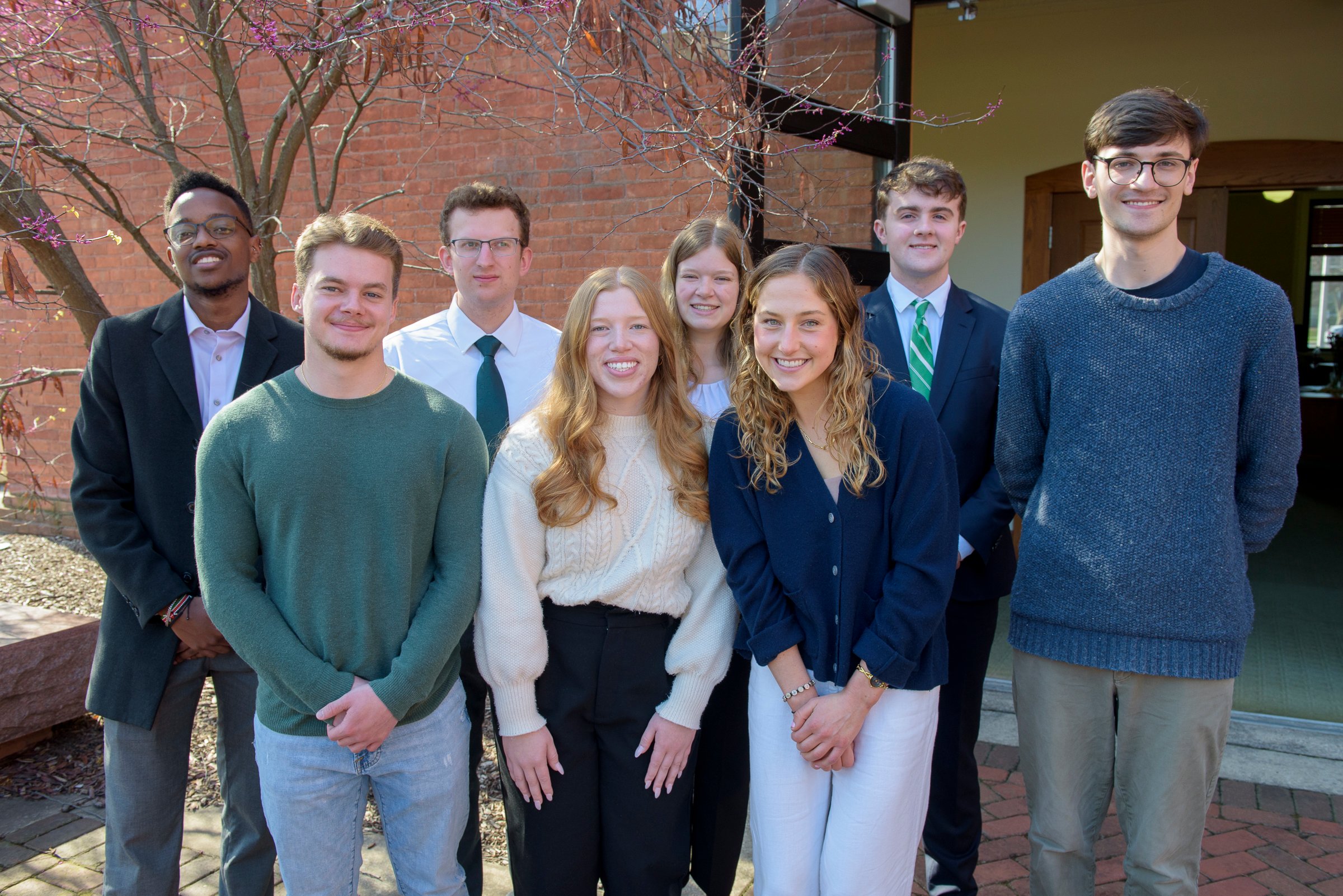 A group of students smiling outside Marshall-Adams Hall.