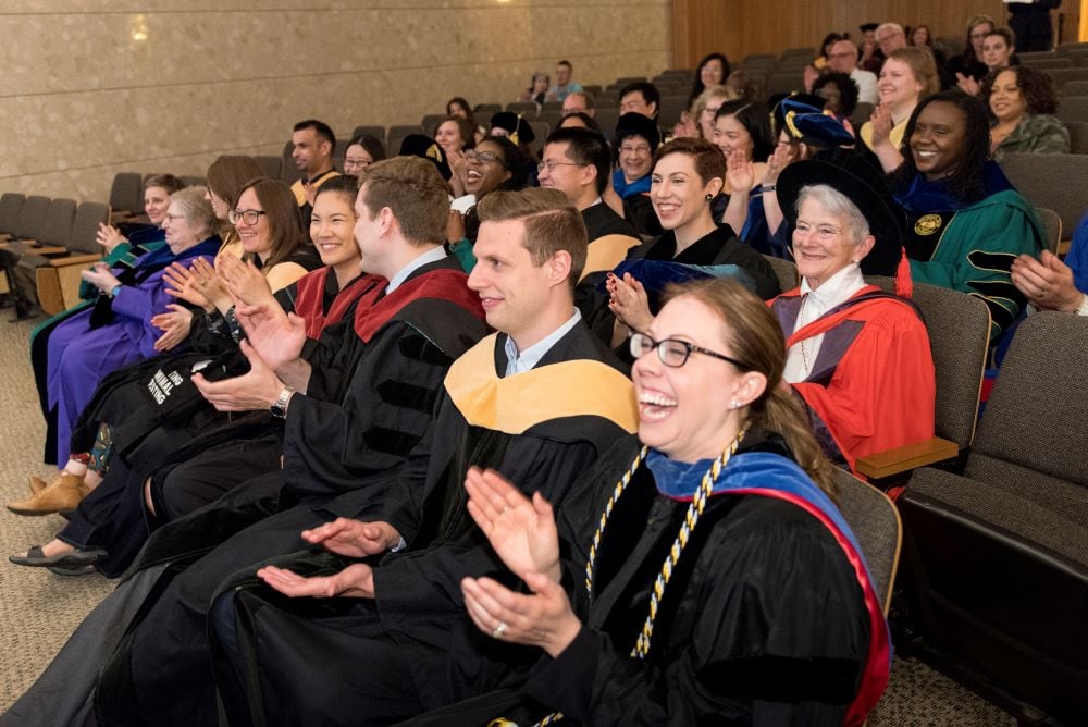 PhD students clap during the ceremony. 