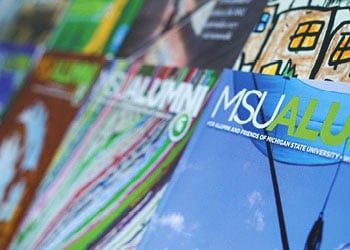 Stacks of MSU Alumni magazine of different colors.