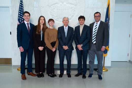 Students and professor stand with fed challenge chairperson.