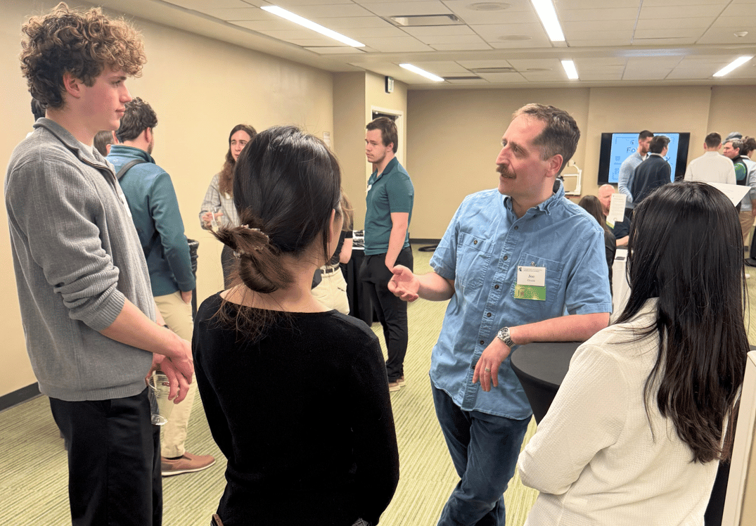 An alumnus speaks with three students.