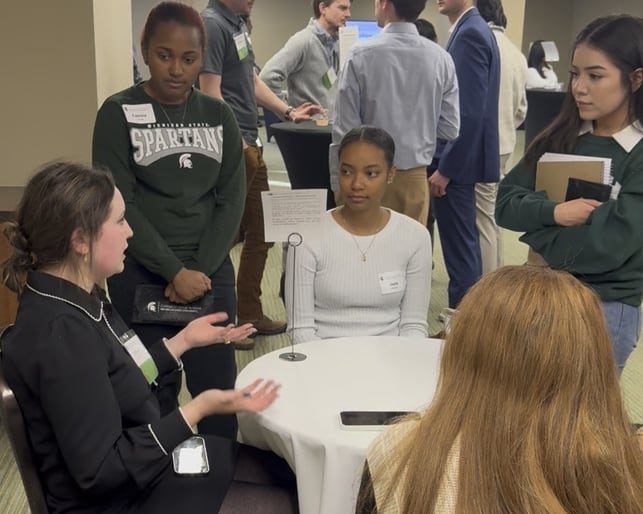 Alumna speaks with four students.