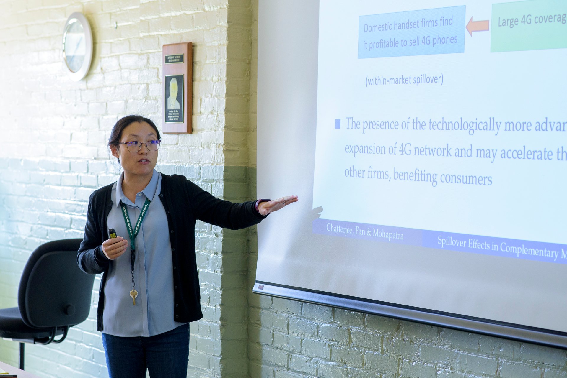 Professor points to screen during seminar. 