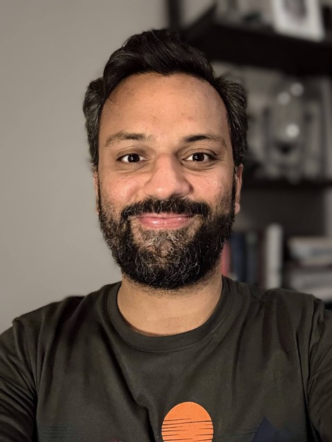 This is a photo of Rohit. He has short black hair, a mustache, and a beard. He is smiling.