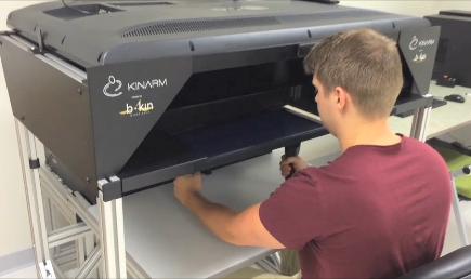 man looking into a robotic machine handing onto the "arms" in the machine