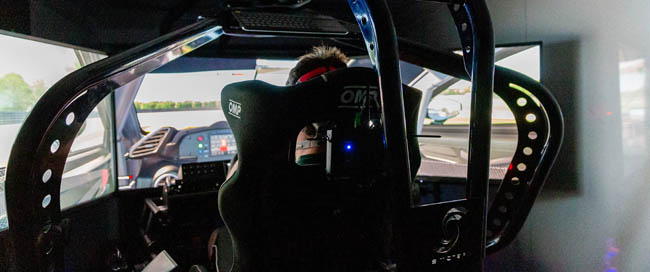 Interior of a racing car simulator with visible steering wheel and equipment.