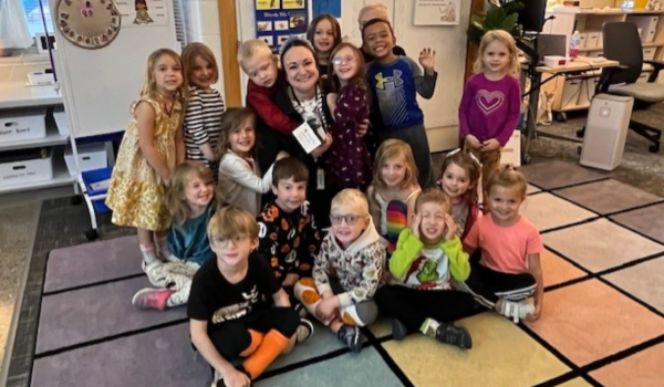 Spartan teacher smiles with group of young students