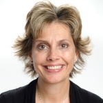 This is a picture of Nicole Zumpano. She has medium to light skin and medium tone, short hair. She is smiling and facing the camera. She is wearing a black blazer and grey shirt.