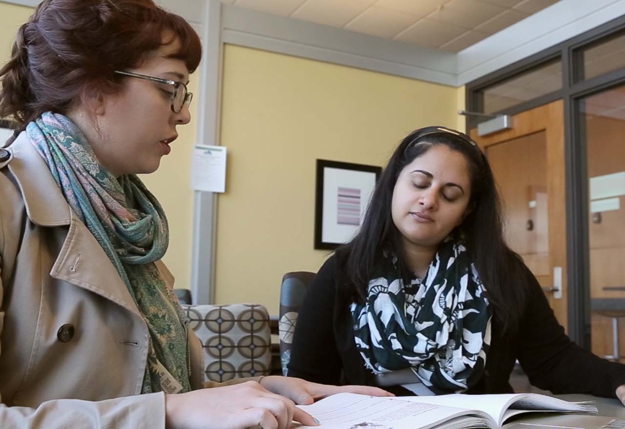 Two students gather in discussion about a project