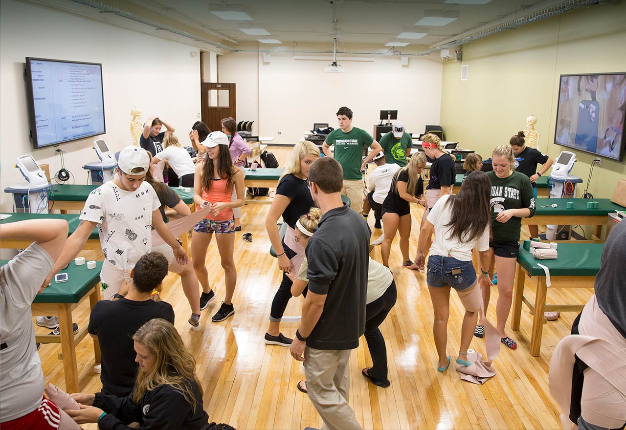 Students work on wrapping injuries in a Kinesiology lab space.
