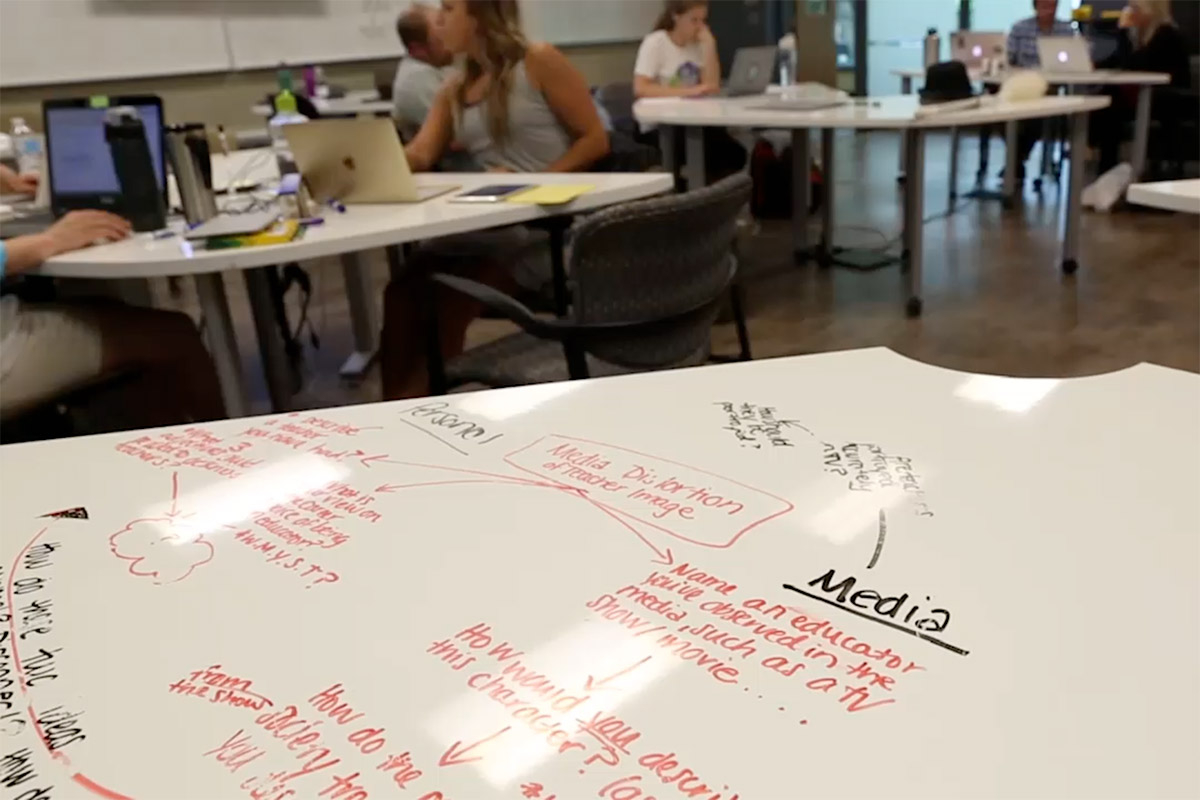 Information is written on a whiteboard in a full classroom