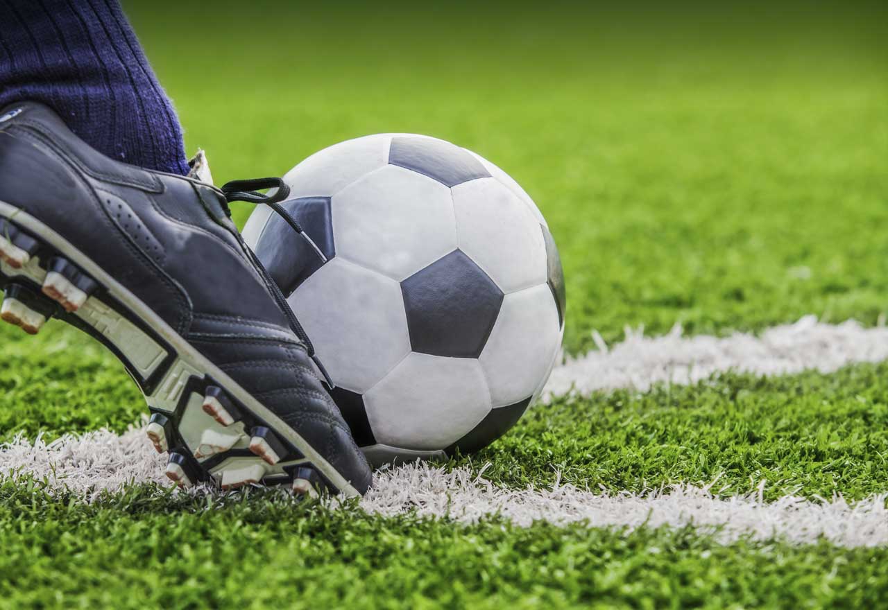 Close-up of a soccer cleat kicking a soccer ball on a field