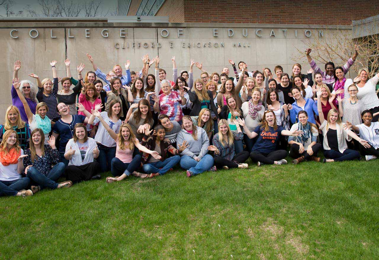 Students in the program smile and wave arms during a photo session