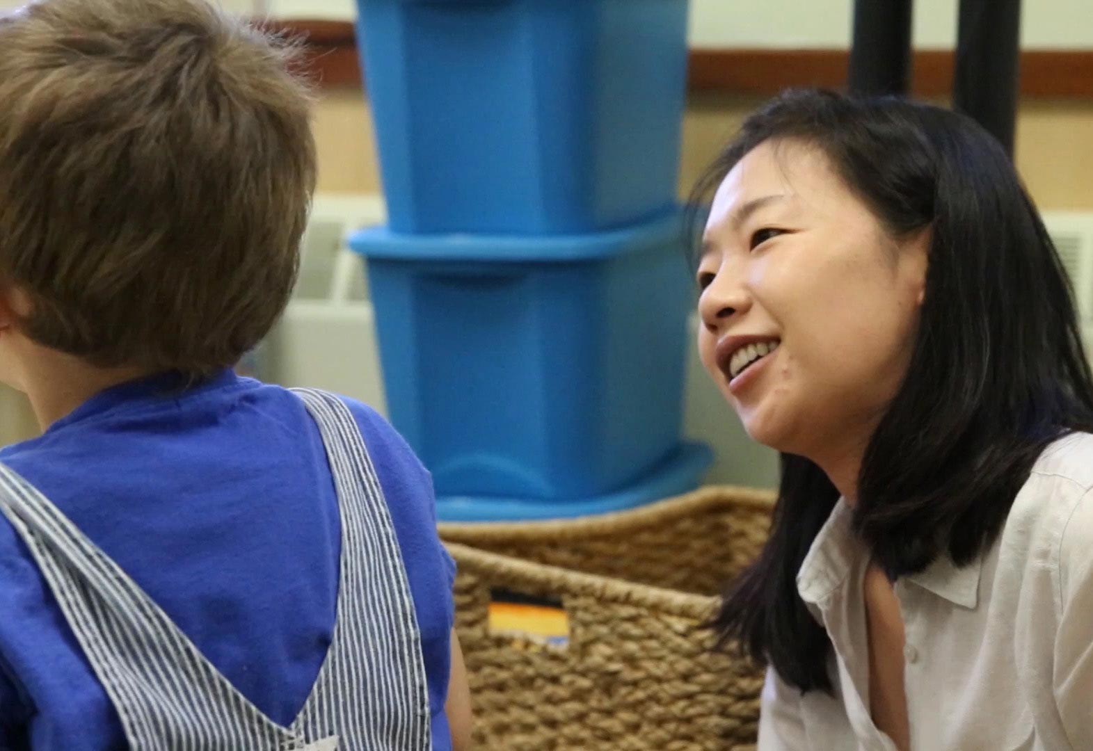 A teacher smiles at a young learner