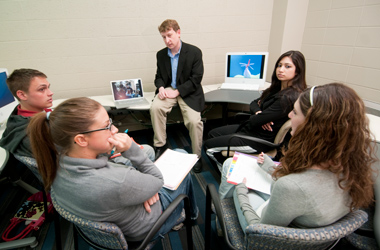 Students collaborate with a faculty member in a circle