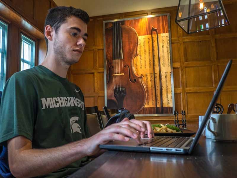 Student working on laptop in a dorm common area