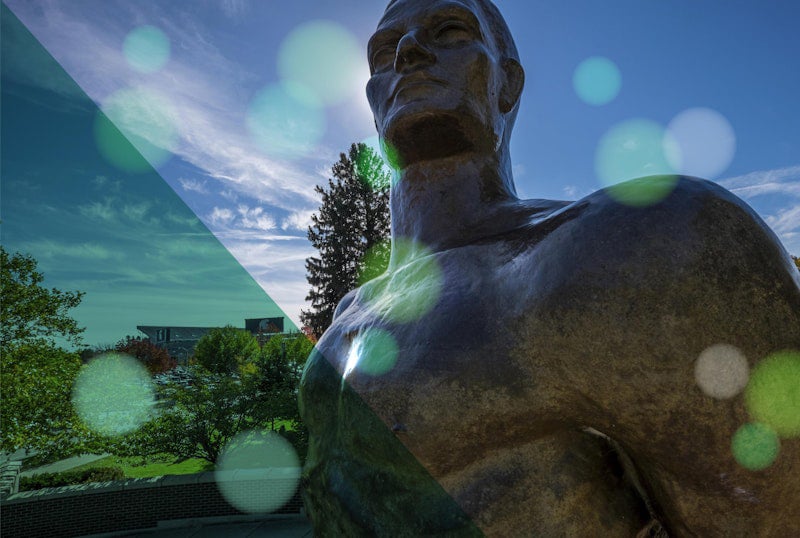 Close up of head and shoulders of Spartan statue with blue sky background and overlay of green transparent bubbles