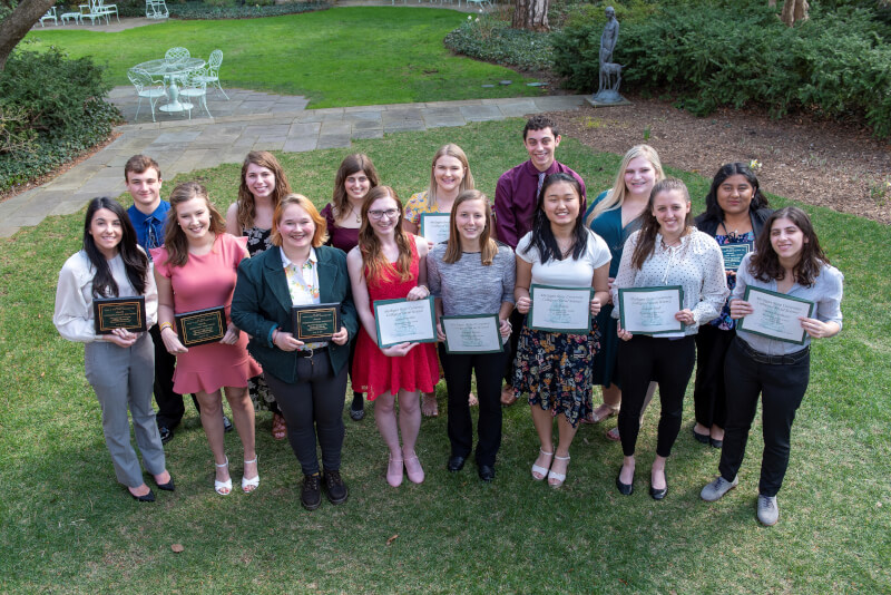 Students smile holding certificates. 