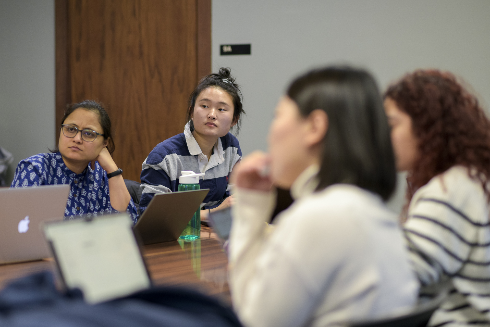 Graduate students and faculty talking at a conference table.