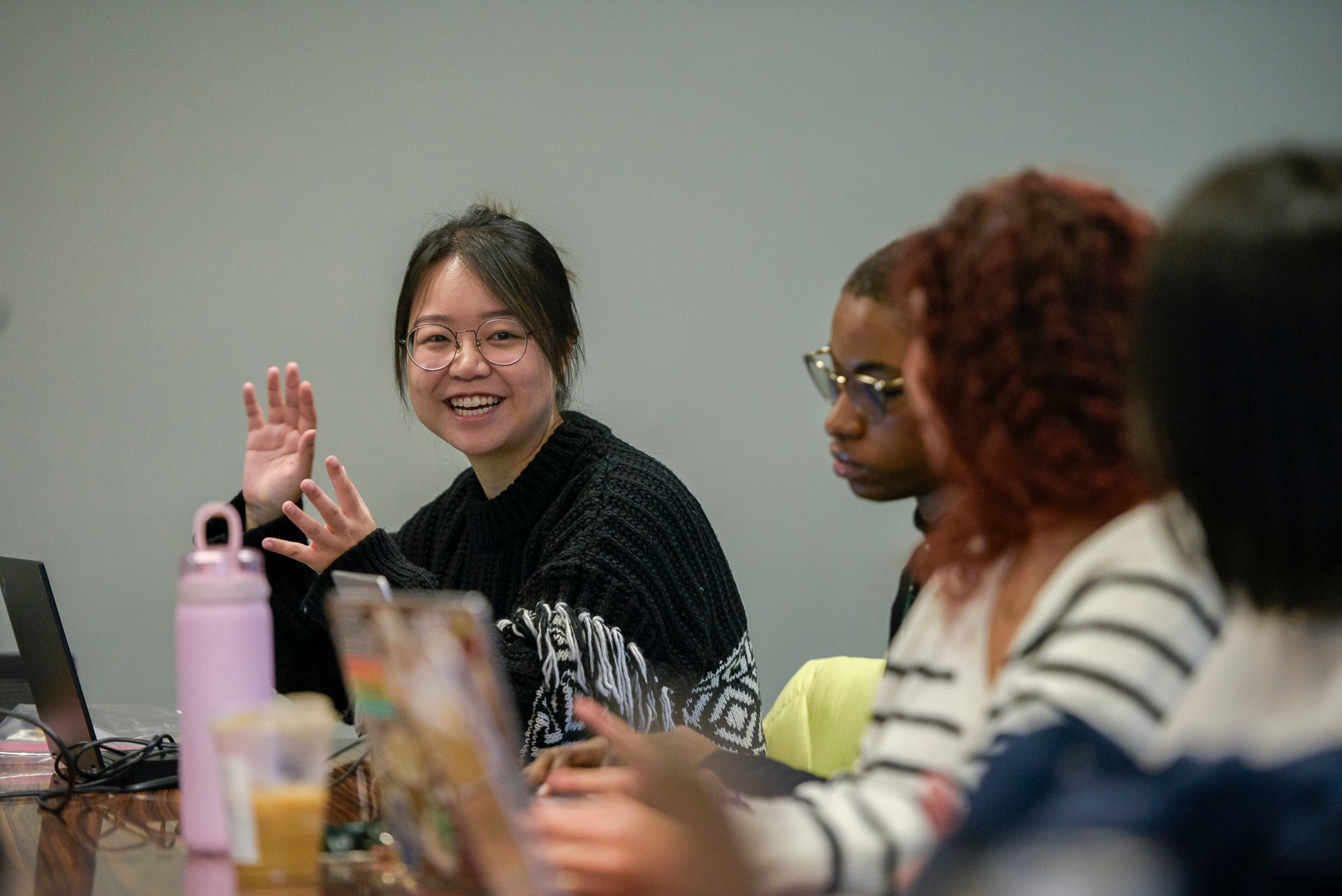 Graduate students and faculty talking at a conference table.