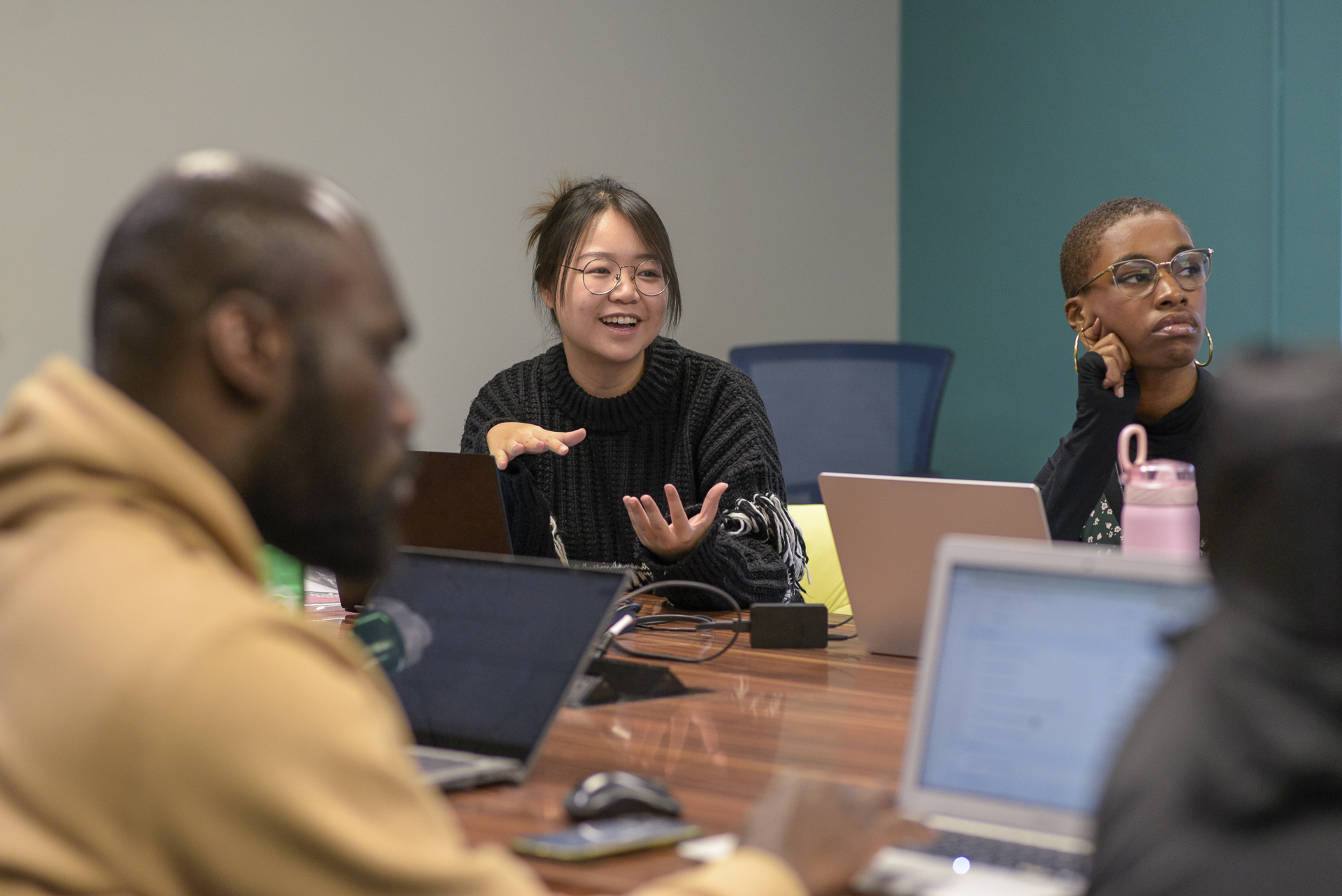 Graduate students and faculty talking at a conference table.