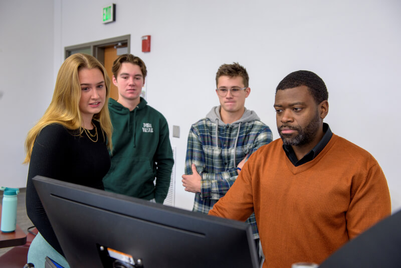 Professor shows concept on computer to students. 